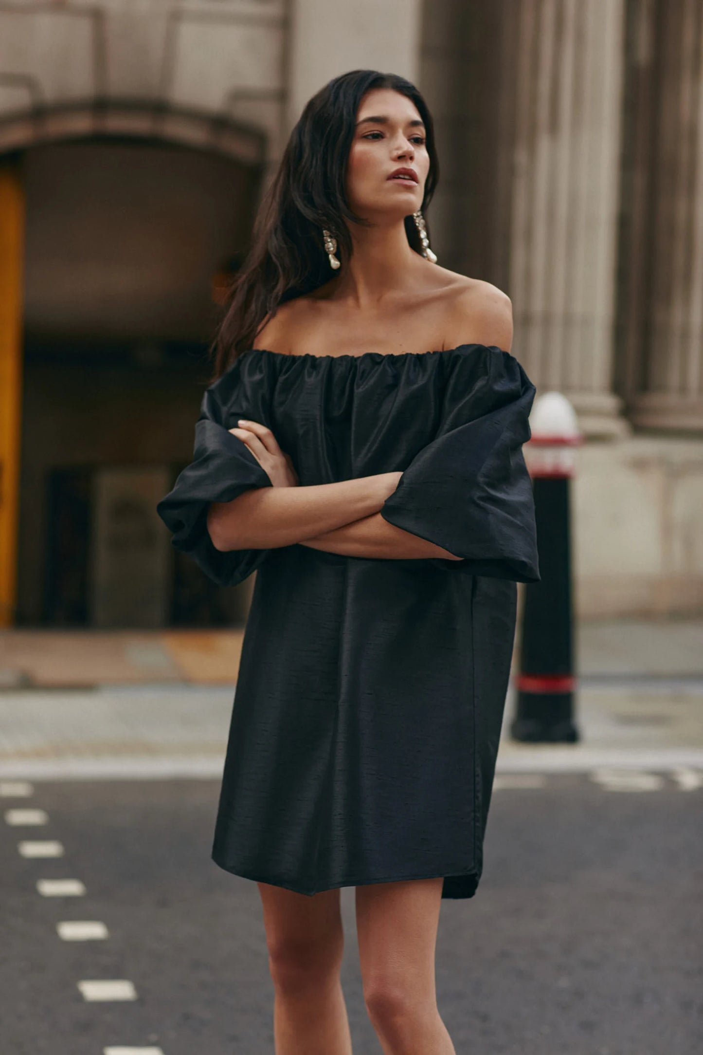 On location Malina Off-shoulder black mini dress with short pouf sleeve and wide fit. The perfect addition to your luxury designer resort wear wardrobe.