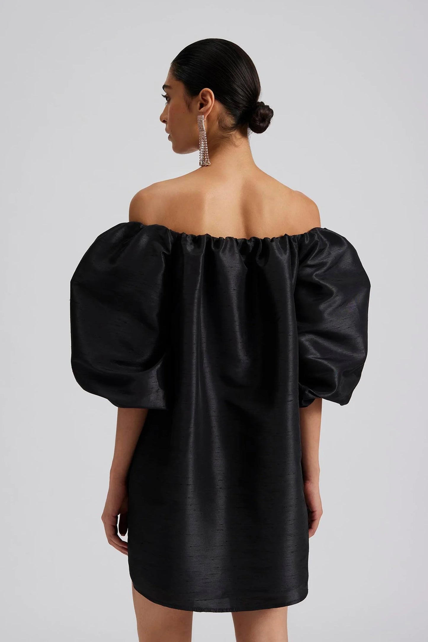 Back facing Malina Off-shoulder black mini dress with short pouf sleeve and wide fit. The perfect addition to your luxury designer resort wear wardrobe.