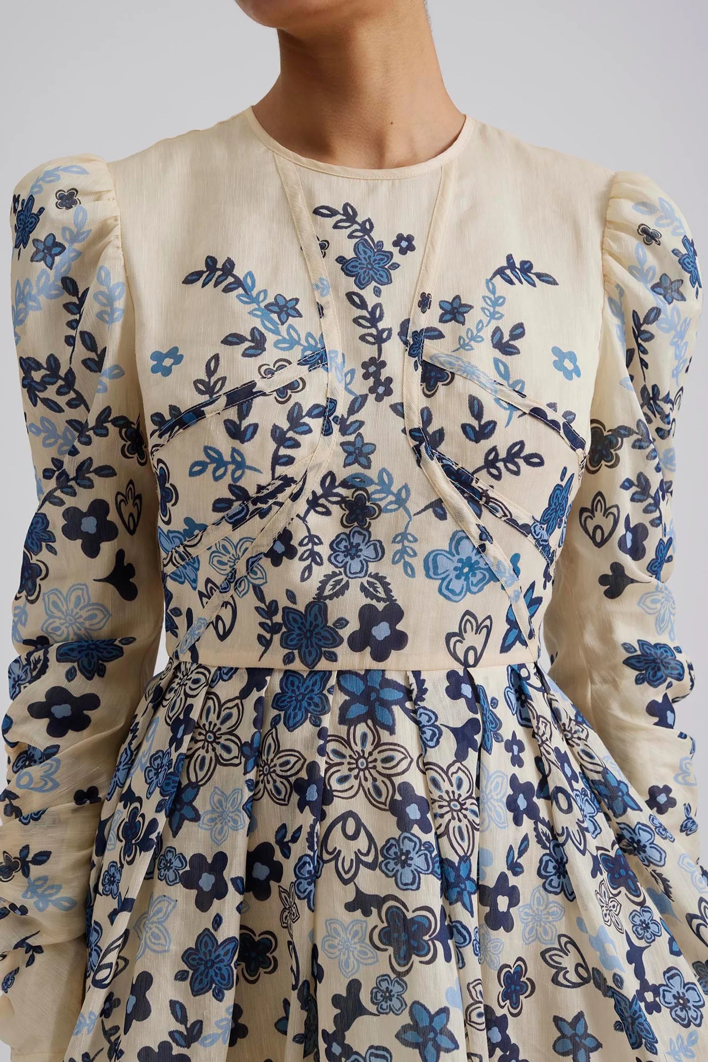 Close up Malina Printed mini dress with long sleeve in silk blend. Expertly crafted from a luxurious silk blend, this Leoni Mini Dress features a stunning coastal floral design. With its elegant silhouette and soft, breathable fabric, this dress is perfect for any occasion. The perfect addition to your luxury designer resort wear wardrobe.