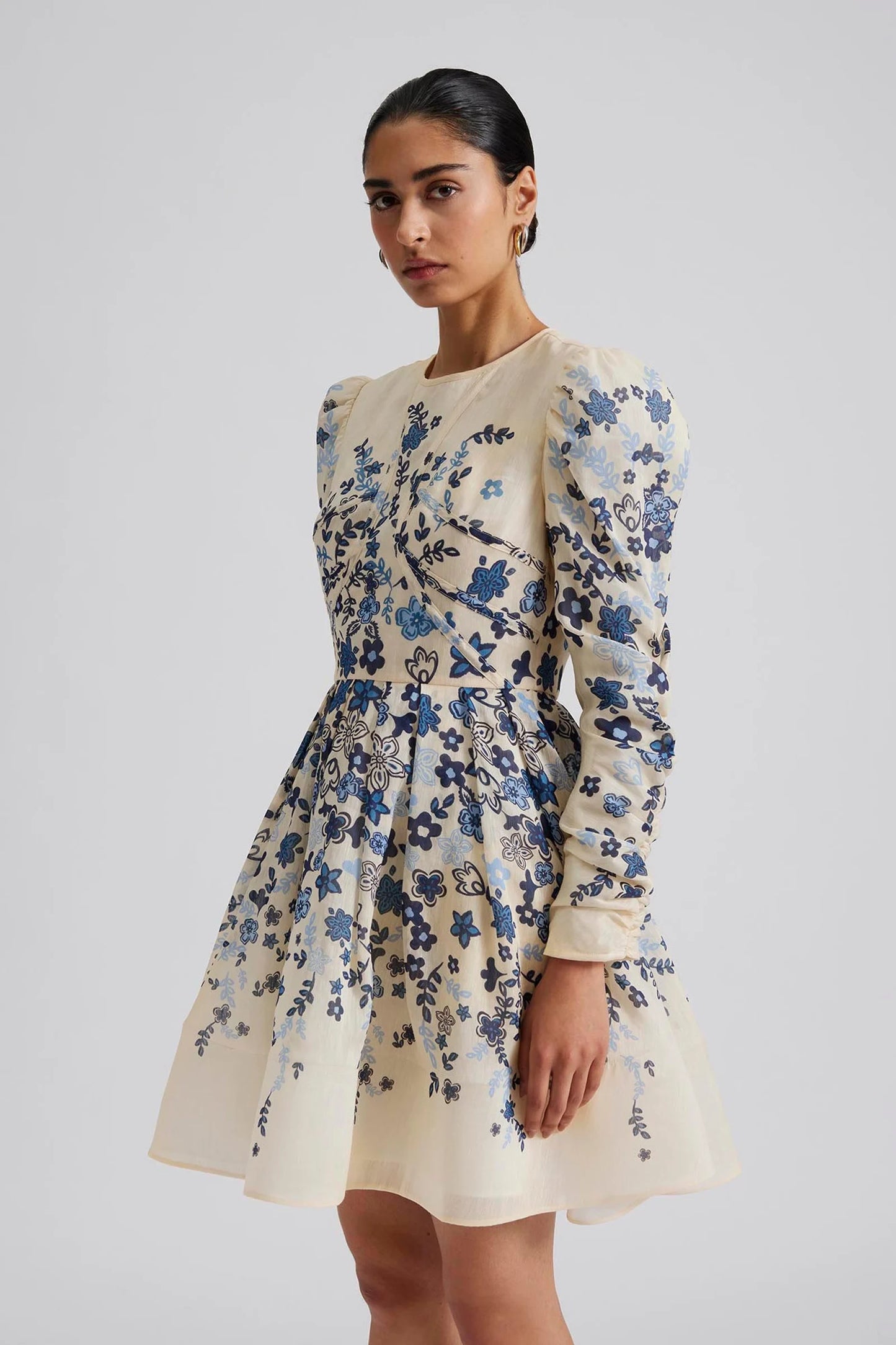 side facing Malina Printed mini dress with long sleeve in silk blend. Expertly crafted from a luxurious silk blend, this Leoni Mini Dress features a stunning coastal floral design. With its elegant silhouette and soft, breathable fabric, this dress is perfect for any occasion. The perfect addition to your luxury designer resort wear wardrobe.