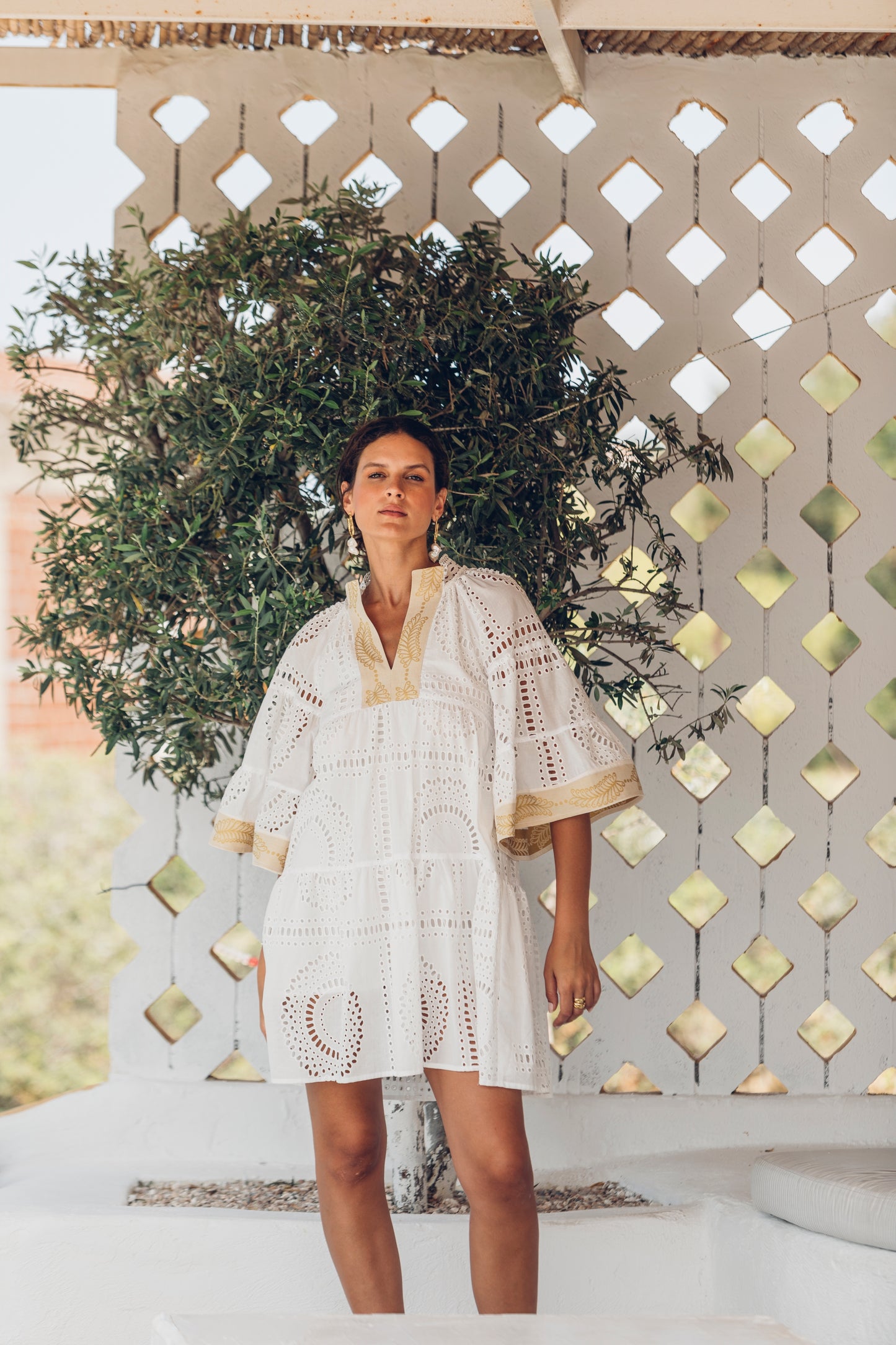 Front facing **PRE-ORDER 1st APRIL** Nema Elle Broderie White Cut Out Mini Dress with gold detail. The perfection addition to your luxury designer resort wear wardrobe.