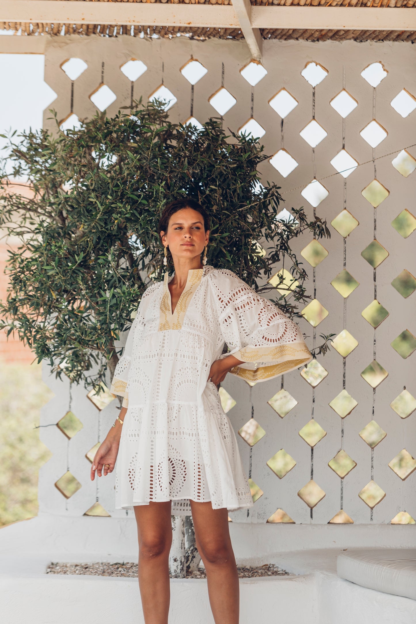 Overview image **PRE-ORDER 1st APRIL** Nema Elle Broderie White Cut Out Mini Dress with gold detail. The perfection addition to your luxury designer resort wear wardrobe.