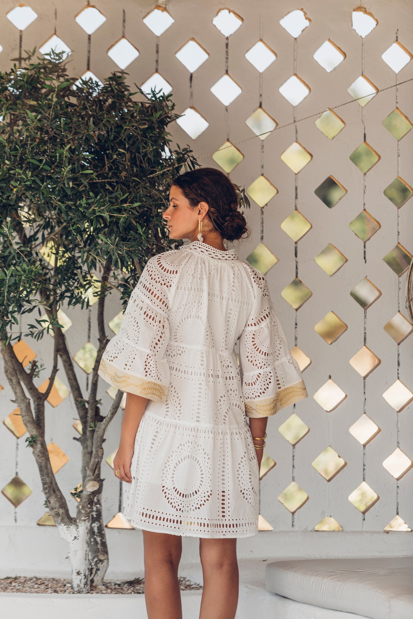 Back facing **PRE-ORDER 1st APRIL** Nema Elle Broderie White Cut Out Mini Dress with gold detail. The perfection addition to your luxury designer resort wear wardrobe.