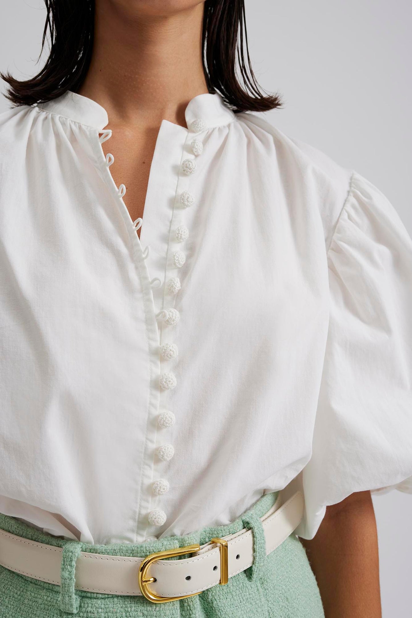 Close up Malina designer Allie Pouf Sleeve Embroidered Blouse in White. With delicate embroidery and elegant pouf sleeves, this blouse exudes sophistication and exclusivity. Perfect for a luxurious evening out or a high-end event on your next luxury trip to paradise.